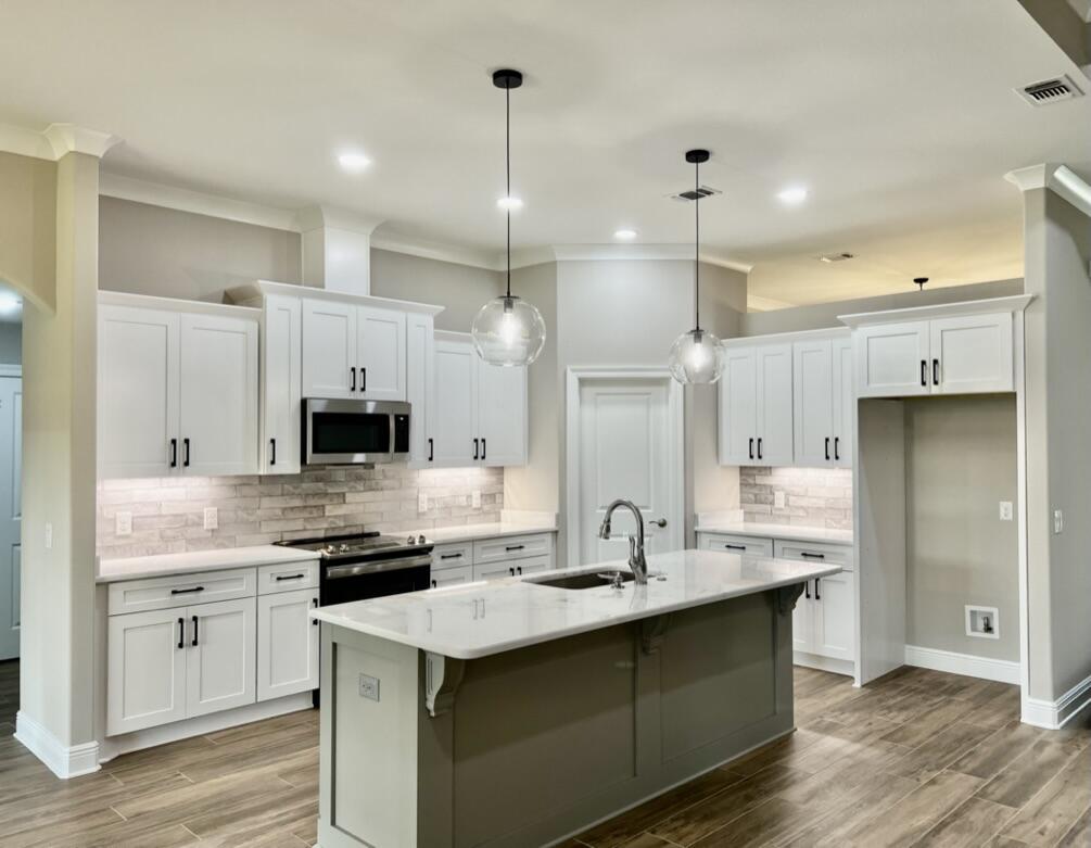 7586 Vinca Street Navarre, FL 32566 - Photo 8 of 44 a kitchen with kitchen island a sink stainless steel appliances and white cabinets