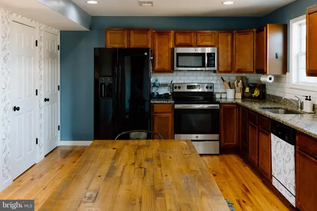 a kitchen with stainless steel appliances granite countertop a stove a refrigerator and a microwave oven