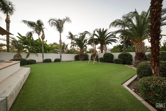 a view of a house with a yard and palm trees