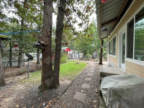 a view of a backyard with table and chairs potted plants and large tree