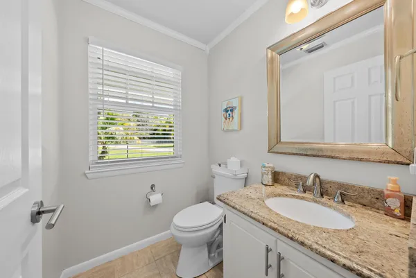 a bathroom with a granite countertop sink toilet and mirror