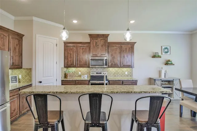 a kitchen with stainless steel appliances granite countertop a table chairs stove and refrigerator