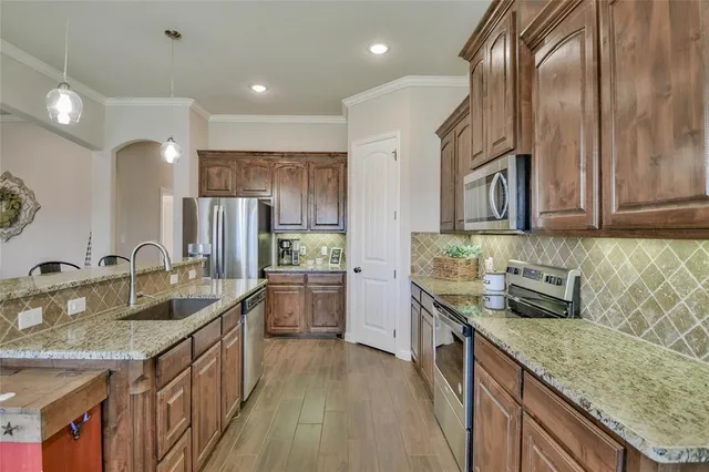 a kitchen with stainless steel appliances granite countertop a sink a stove and a refrigerator