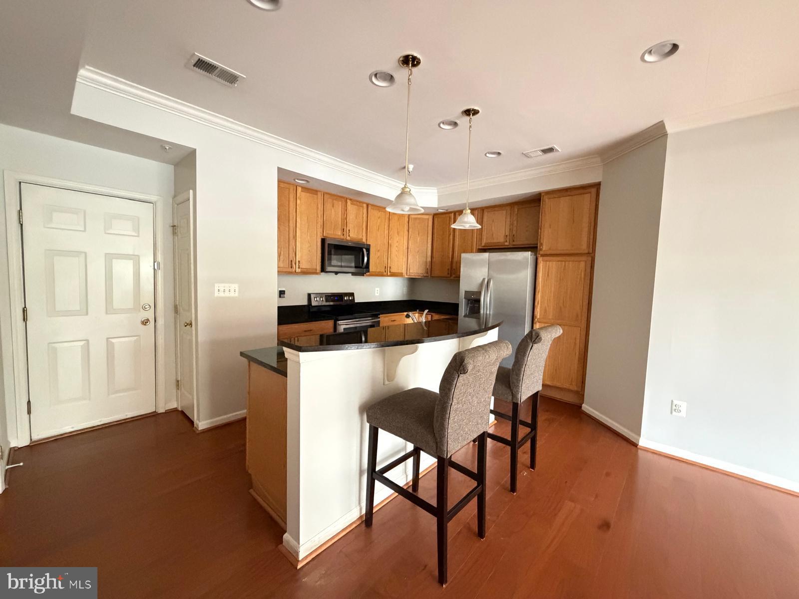 7248 Elkridge Crossing Way Elkridge, MD 21075 - Photo 4 of 47 a kitchen with stainless steel appliances a refrigerator a stove a microwave oven a sink with island and chairs