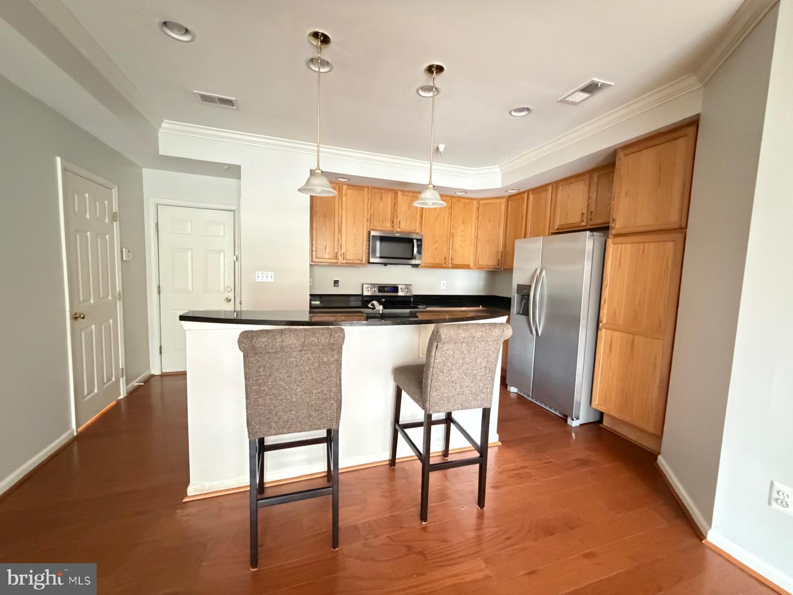 7248 Elkridge Crossing Way Elkridge, MD 21075 - Photo 7 of 47 a kitchen with stainless steel appliances granite countertop a refrigerator a stove a microwave oven a sink with island and chairs with wooden floor