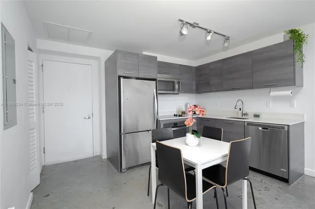 a kitchen with a table chairs refrigerator and cabinets