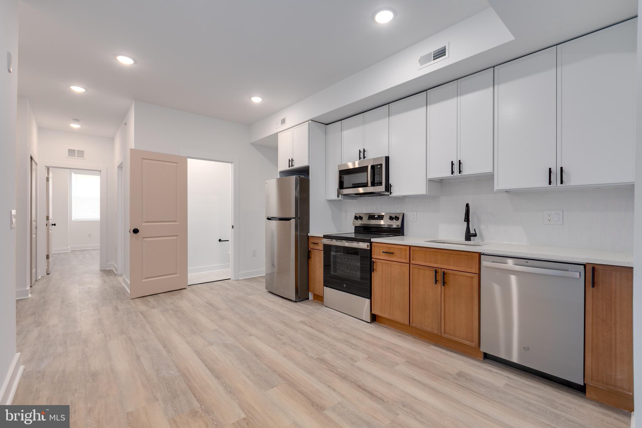 2061 North 8th Street, Unit 3 Philadelphia, PA 19122 - Photo 2 of 11 a open kitchen with stainless steel appliances granite countertop a stove a sink and white cabinets