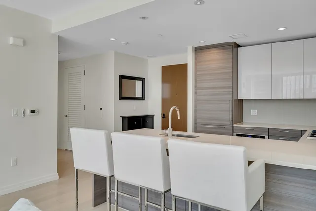 a kitchen with stainless steel appliances a white table chairs and a refrigerator