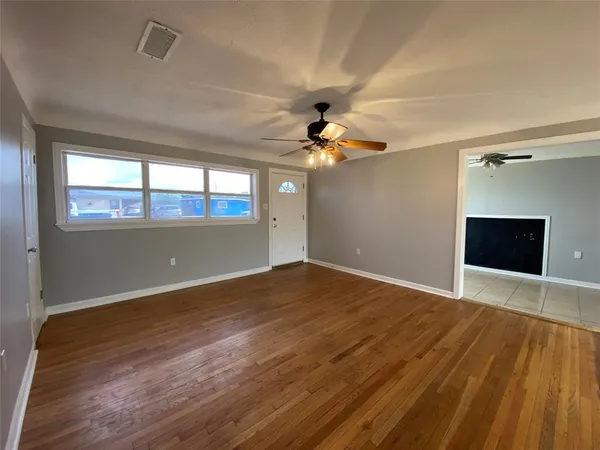 a view of an empty room with a window and wooden floor