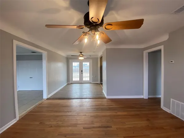 a view of an empty room with a window and wooden floor