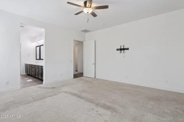 an empty room with wooden floor and a ceiling fan