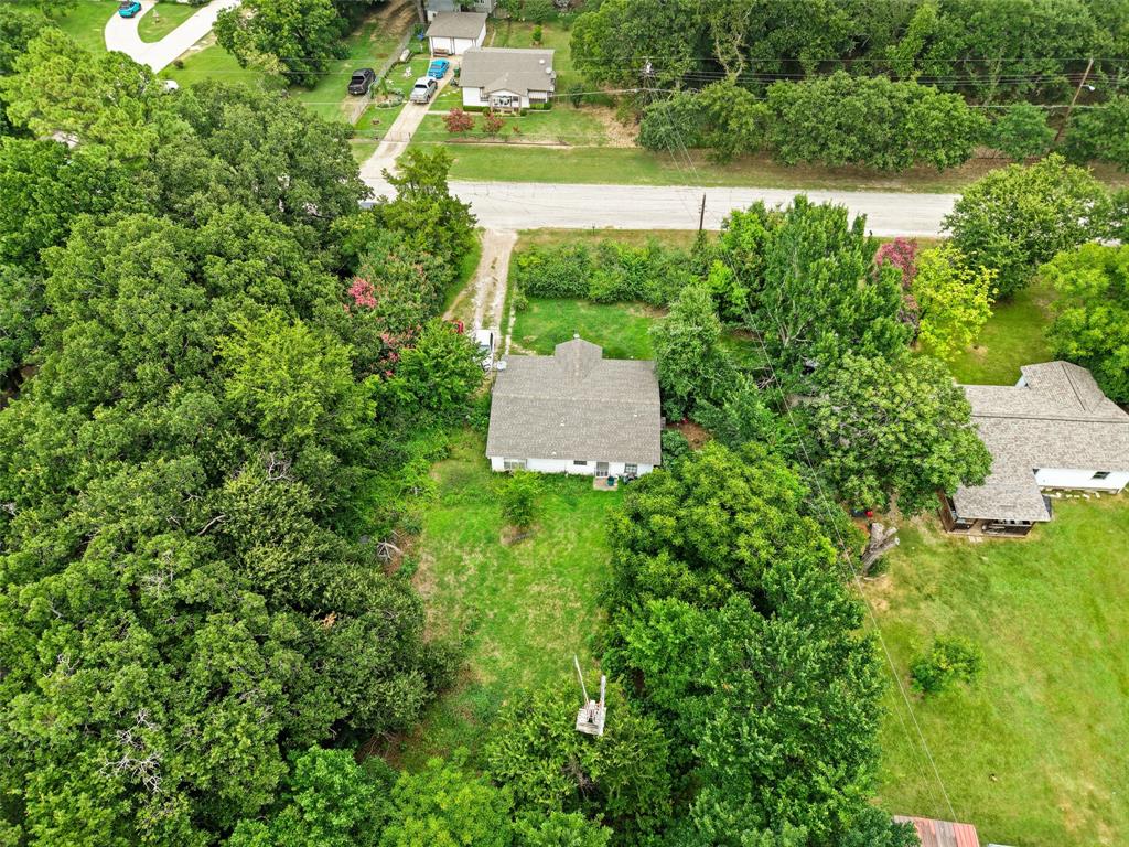 2503 Kleberg Road Seagoville, TX 75159 - Photo 3 of 10 Aerial perspective of a single-story residence featuring a gray shingle roof and white siding, surrounded by mature trees