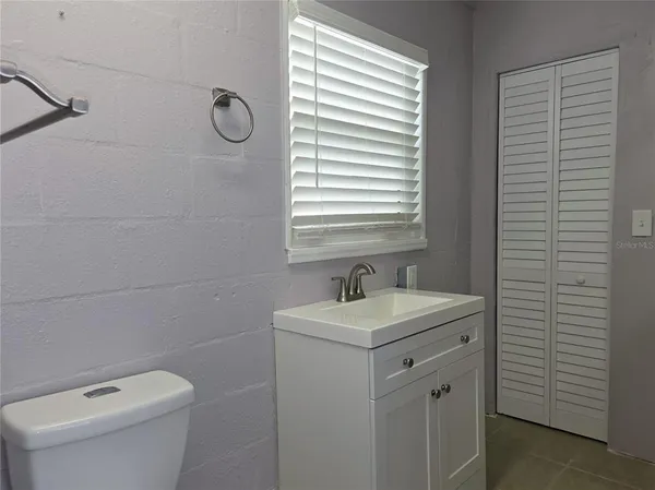 a bathroom with a toilet a sink a window and shower