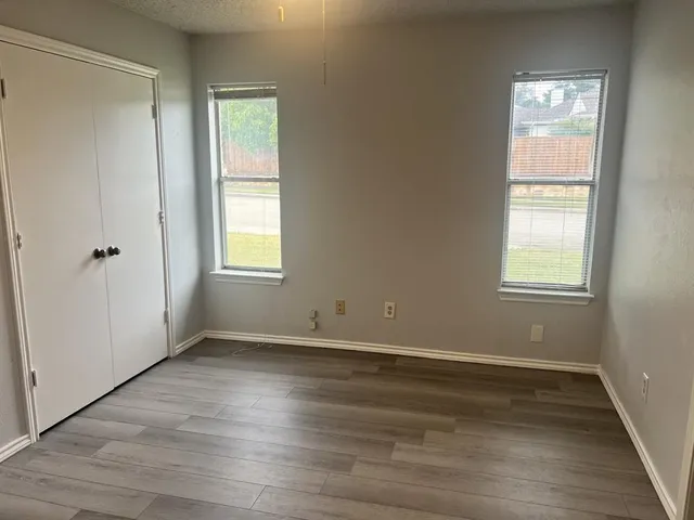 an empty room with wooden floor and windows