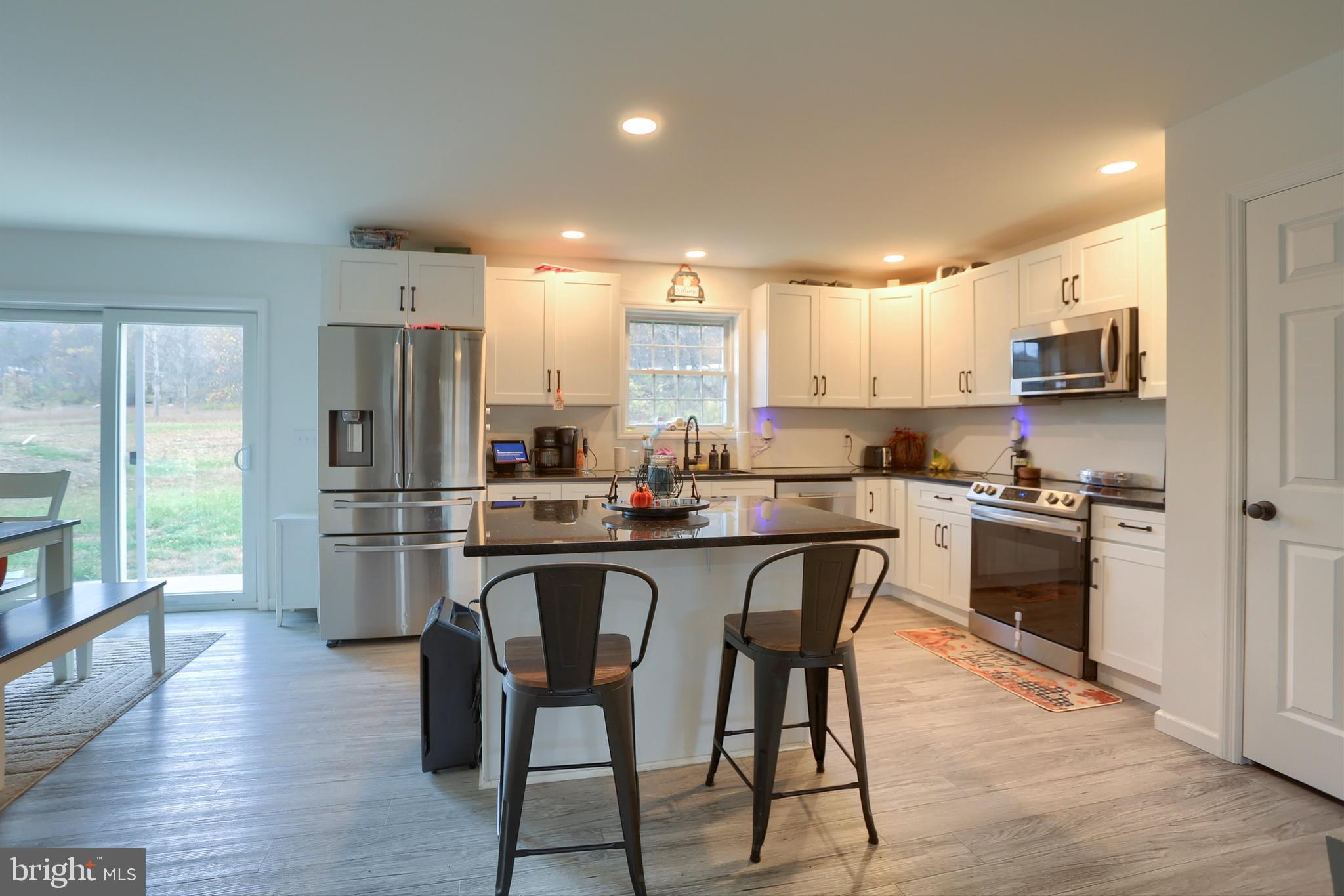 405 Small Valley Road Halifax, PA 17032 - Photo 11 of 36 a kitchen with stainless steel appliances a stove a sink dishwasher a refrigerator and a dining table with wooden floor