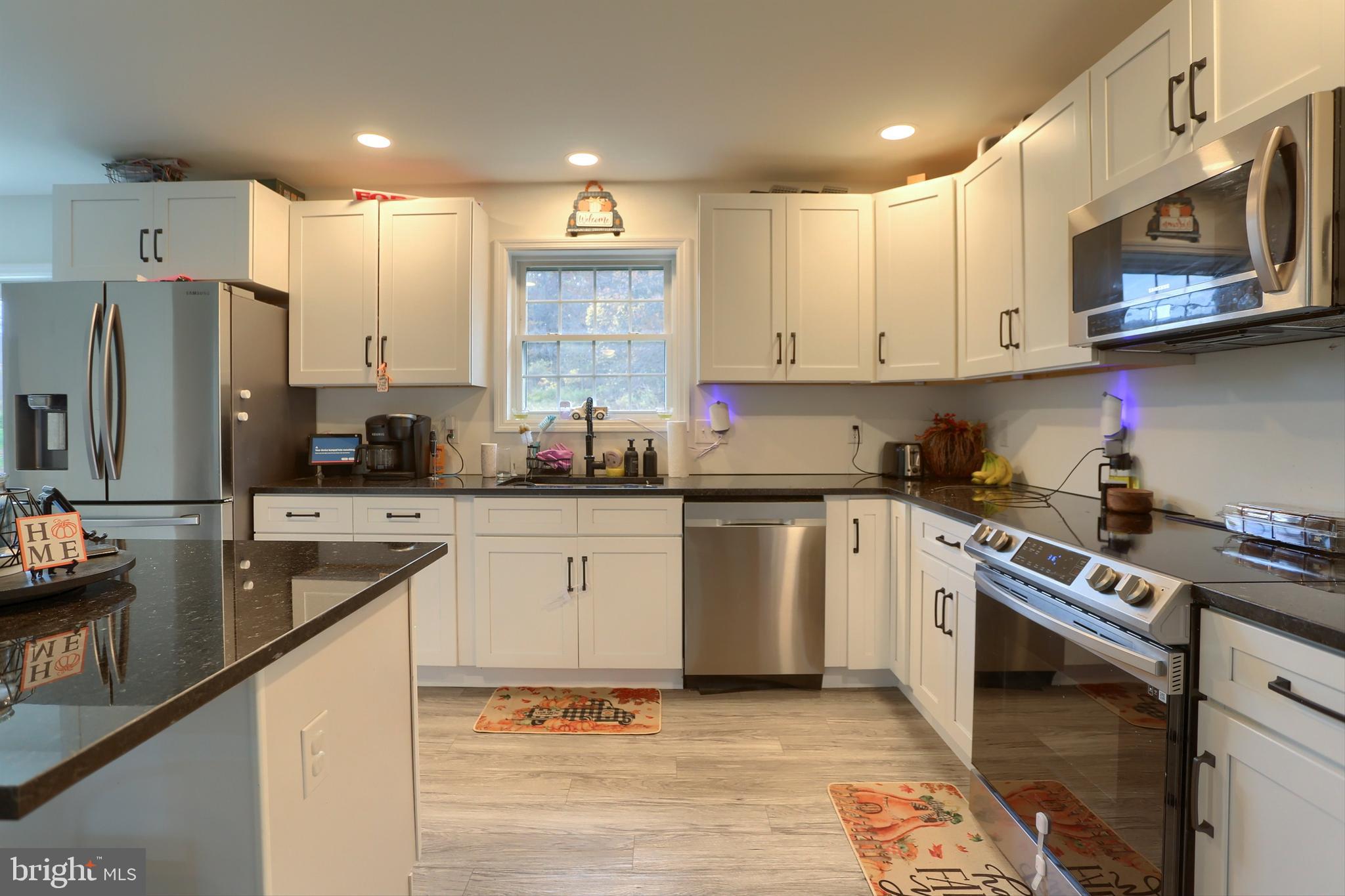405 Small Valley Road Halifax, PA 17032 - Photo 17 of 36 a kitchen with stainless steel appliances granite countertop a stove a sink dishwasher a refrigerator and white cabinets with wooden floor