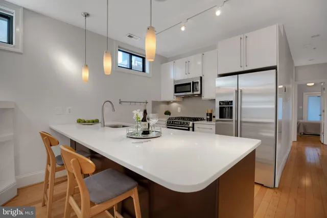 a kitchen with kitchen island white cabinets appliances and wooden floor
