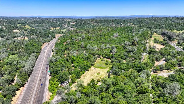 an aerial view of residential house with outdoor space and trees all around