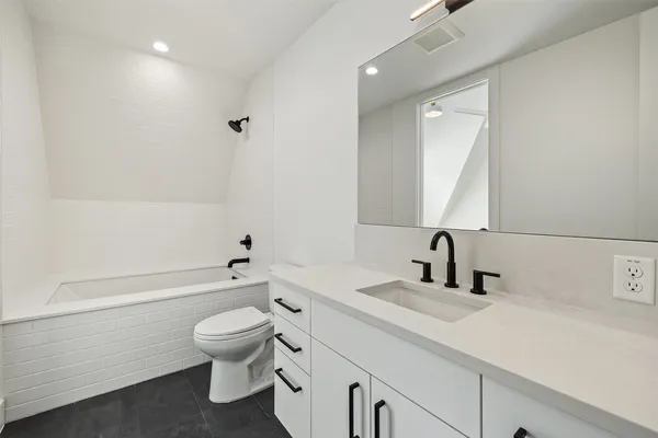 a bathroom with a toilet a sink a mirror and a bathtub