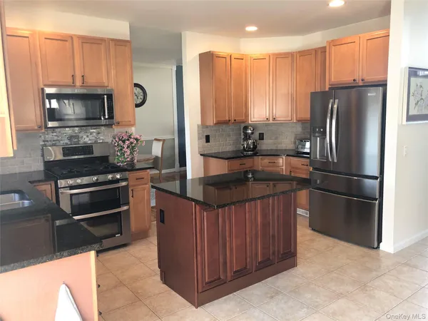 a kitchen with stainless steel appliances a stove a sink a microwave a refrigerator and cabinets