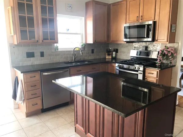 a kitchen with stainless steel appliances granite countertop a stove a sink and a microwave