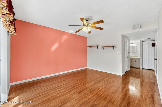 a view of a room with wooden floor and a ceiling fan