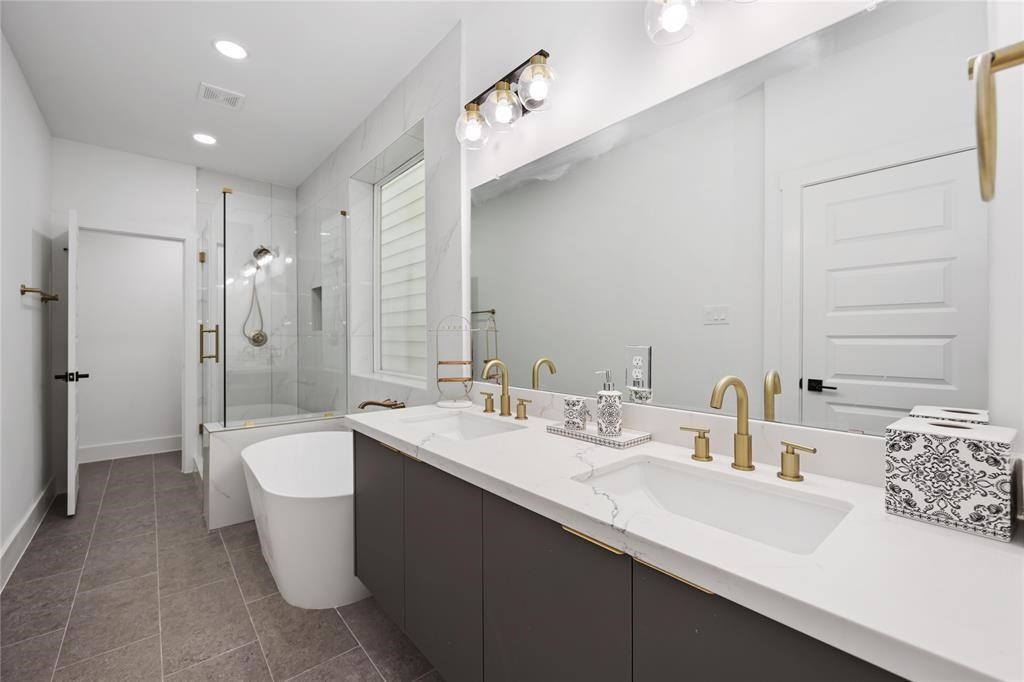 1805 Emir Street, Unit L Houston, TX 77009 - Photo 16 of 35 Take a look at this lovely bathroom - sleek white quartz countertops, dual sinks with brushed gold finish, a soaking tub, and a separate glass enclosed shower complete this bath. Modern custom cabinets provide ample storage for all your needs.