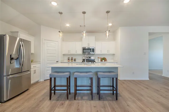 a kitchen with kitchen island a wooden floor and white appliances