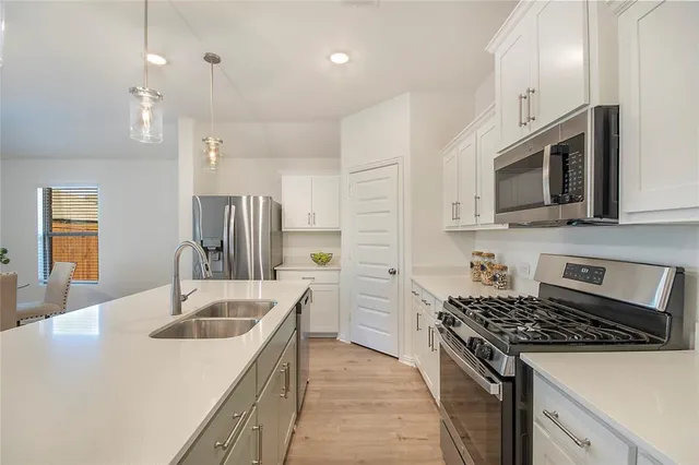 a kitchen with stainless steel appliances granite countertop a sink stove microwave and refrigerator