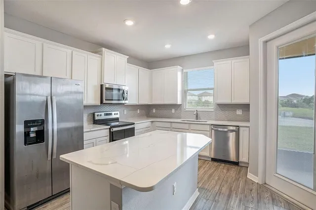 a kitchen with a refrigerator a sink a stove a microwave and cabinets