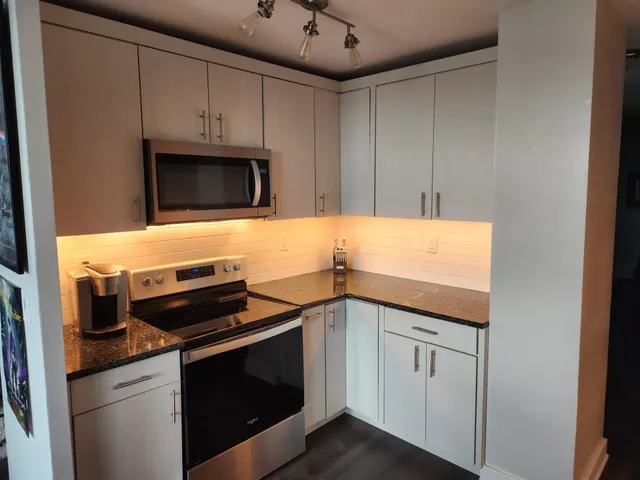 a kitchen with granite countertop cabinets stainless steel appliances and wooden floor