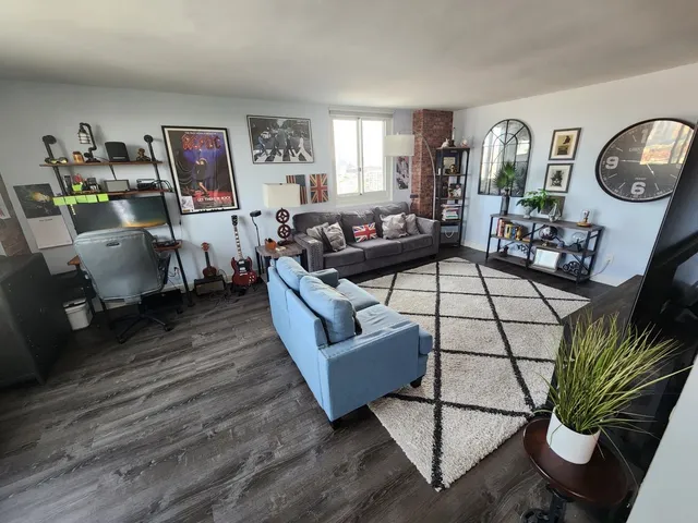 a living room with furniture a clock on wall and a window