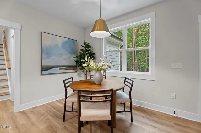 a kitchen with stainless steel appliances granite countertop a stove top oven a sink a dining table and chairs with wooden floor