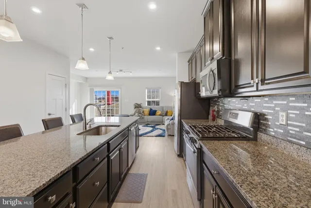 a kitchen with granite countertop a sink a counter space appliances and cabinets