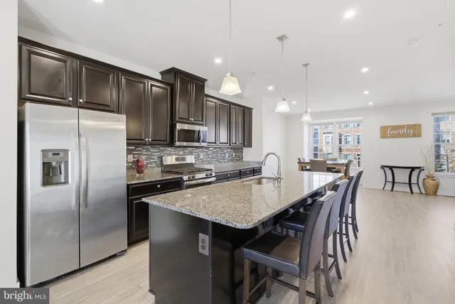 a kitchen with stainless steel appliances granite countertop a refrigerator a stove a sink a table and chairs