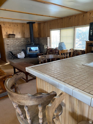 913 East 5300 North Helper, UT 84526 - Photo 29 of 29 Kitchen featuring tile countertops, a wood stove, wooden walls, open floor plan, and a kitchen breakfast bar