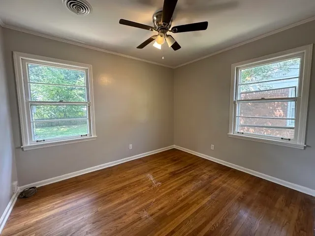 a view of an empty room with window and wooden floor