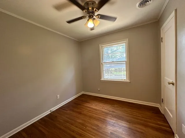 a view of an empty room with window and wooden floor
