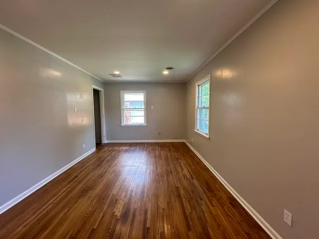 a view of an empty room with wooden floor and window