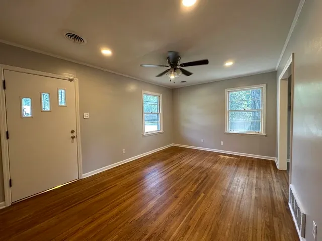 a view of an empty room with wooden floor and a window