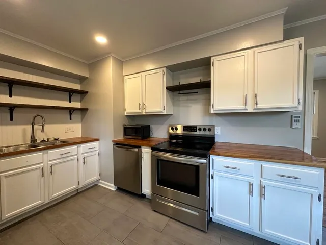 a kitchen with stainless steel appliances granite countertop white cabinets a sink and dishwasher a stove top oven