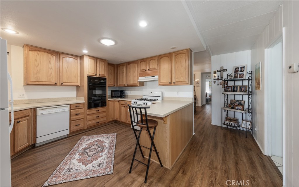 4133 West Wilson Street, Unit 168 Banning, CA 92220 - Photo 12 of 25 a kitchen with stainless steel appliances granite countertop a refrigerator oven a sink dishwasher and white cabinets with wooden floor