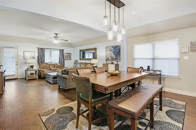 a view of a dining room and livingroom with furniture wooden floor a rug a painting and a chandelier