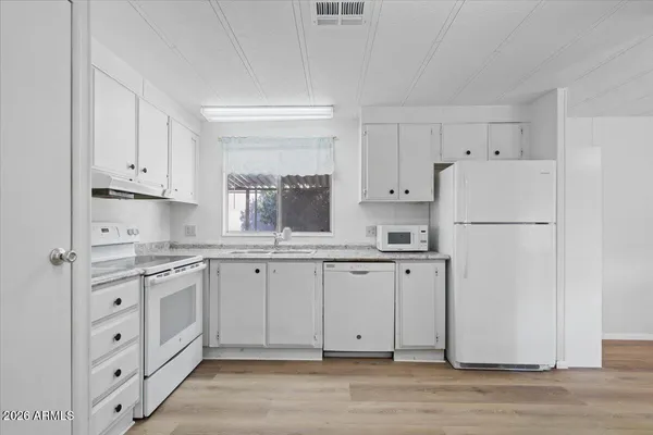 a kitchen with white cabinets white stainless steel appliances and sink