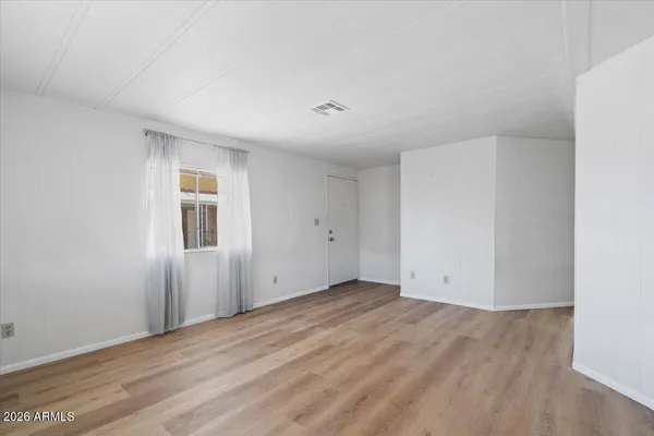 a view of an empty room with wooden floor and closet