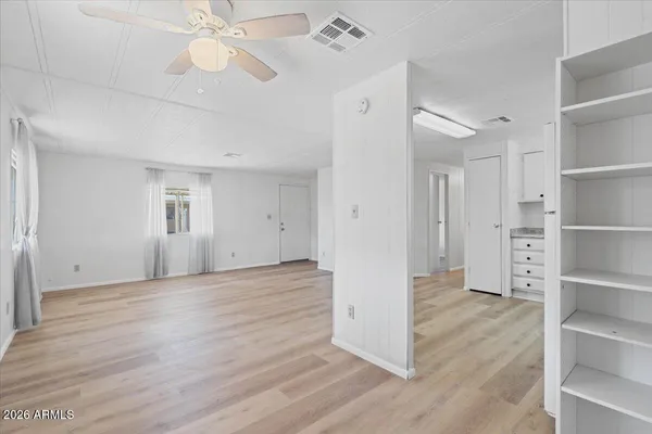 a view of empty room with wooden floor and fan