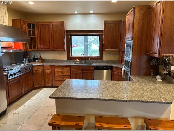 a kitchen with kitchen island granite countertop a stove a sink and a microwave