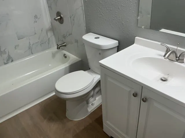 a white toilet sitting next to a bath tub