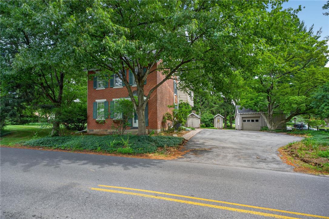 765 East Macada Road Bethlehem, PA 18017 - Photo 3 of 46 A brick facade residence with shuttered windows is framed by mature trees, alongside a detached garage.