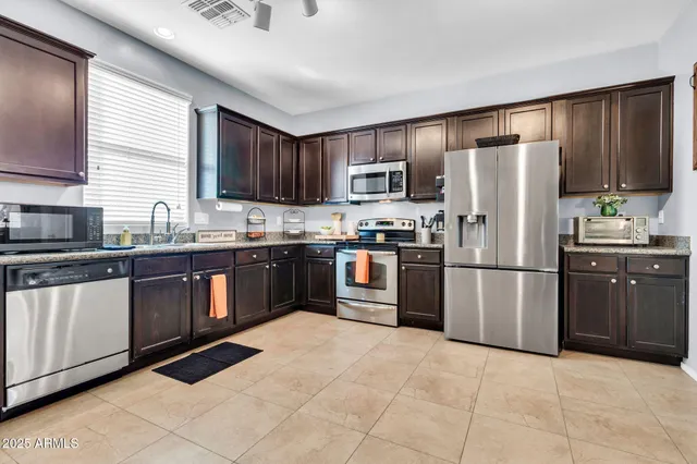 a kitchen with granite countertop a refrigerator stove top oven and cabinets